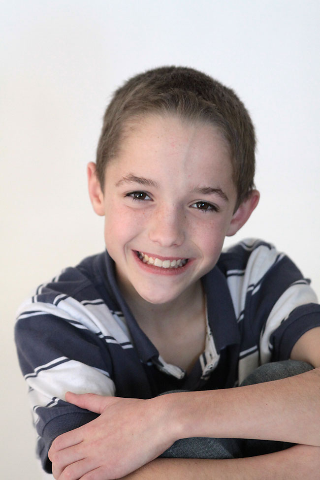 A boy posing for the camera in front of white Seamless Paper