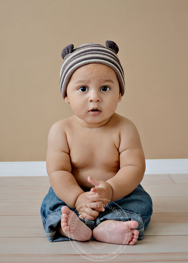 A little boy baby in front of a brown background