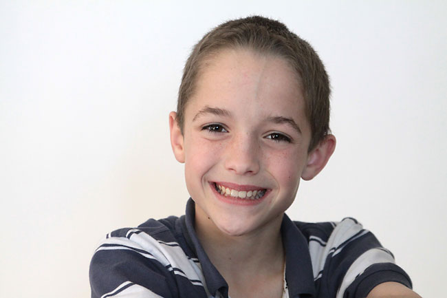 A boy posing for the camera, with white Seamless Paper behind him