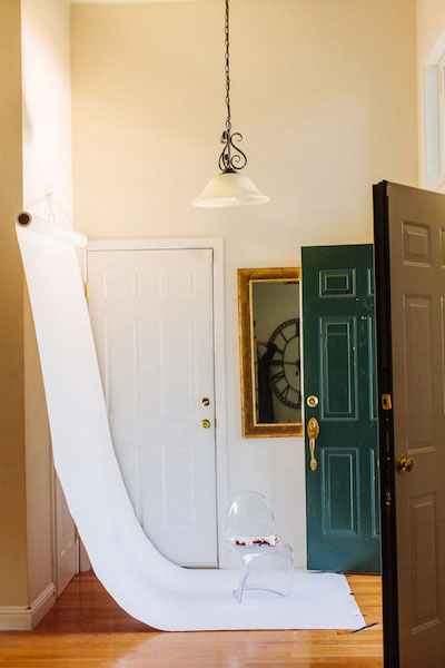 White roll of seamless paper hanging from a hook on the wall, extending onto the floor in front of open doors