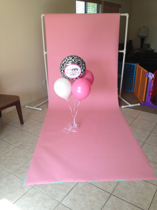 Pink seamless backdrop paper hanging from a DIY backdrop stand