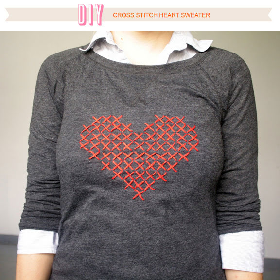 A person wearing a sweater with DIY cross stitch heart on it
