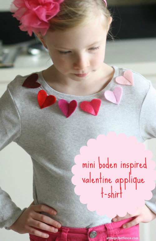A little girl in a grey shirt with pink hearts around the neckline for valentines day