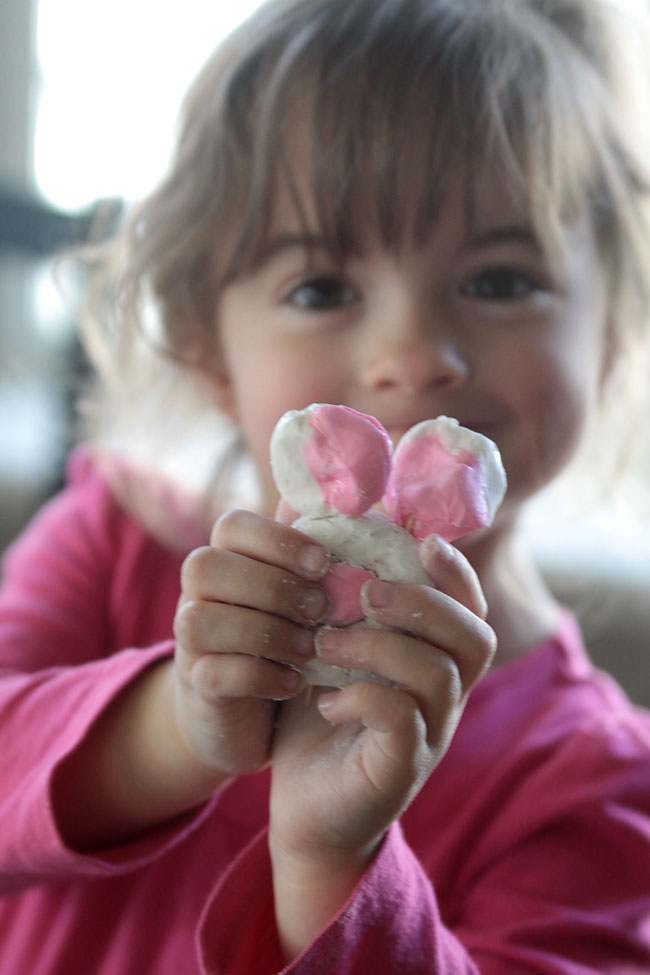 A little girl that is holding a powdered donut bunny treat