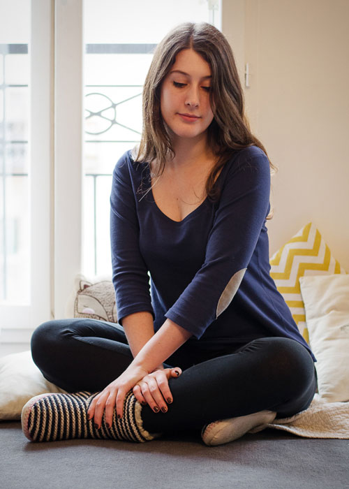 A woman sitting on a chair wearing a long sleeve t-shirt with elbow patches