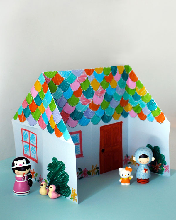 Little house made from folded paper along with tiny toy people