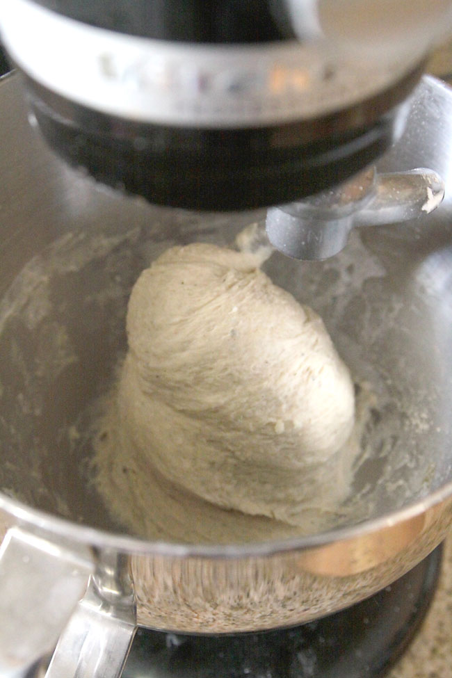 Dinner roll dough in a mixing bowl, pulling away from the sides