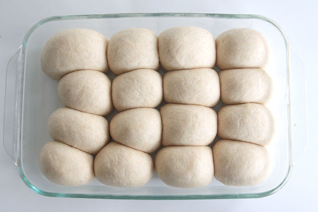balls of roll dough that have risen in a baking dish