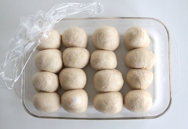 Risen roll dough balls in a 9x13 glass pan