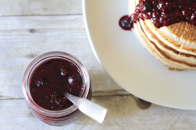 A jar of low sugar berry topping next to a stack of pancakes