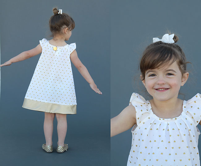 A little girl wearing a flutter sleeve dress with faux leather trim at the hem