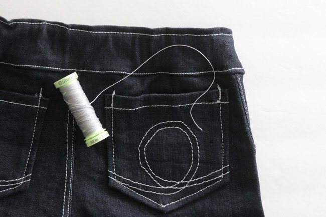 closeup of the pocket on the back of a pair of skinny jeans and spool of thread