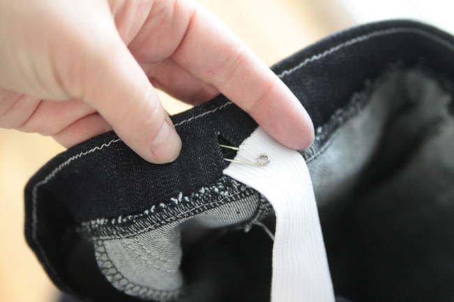 Using a safety pin to thread elastic into waistband of skinny jeans