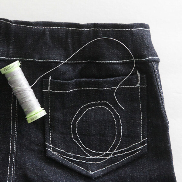 A closeup of the back pocket of a pair of skinny jeans and light grey thread
