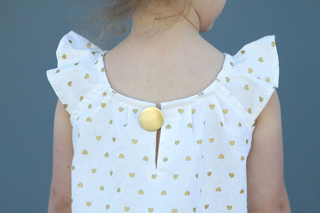 close up of back of dress showing large gold button closure