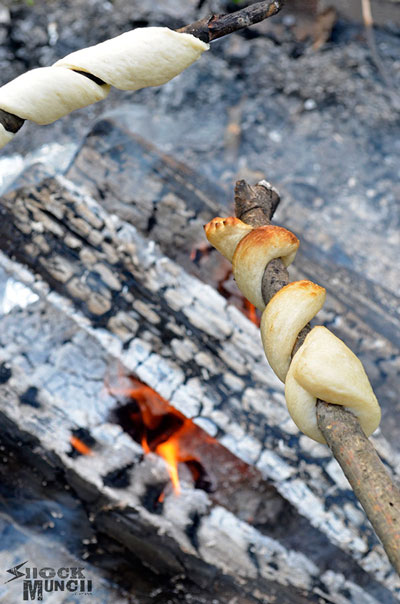 Biscuit dough wrapped around a stick getting cooked over a fire