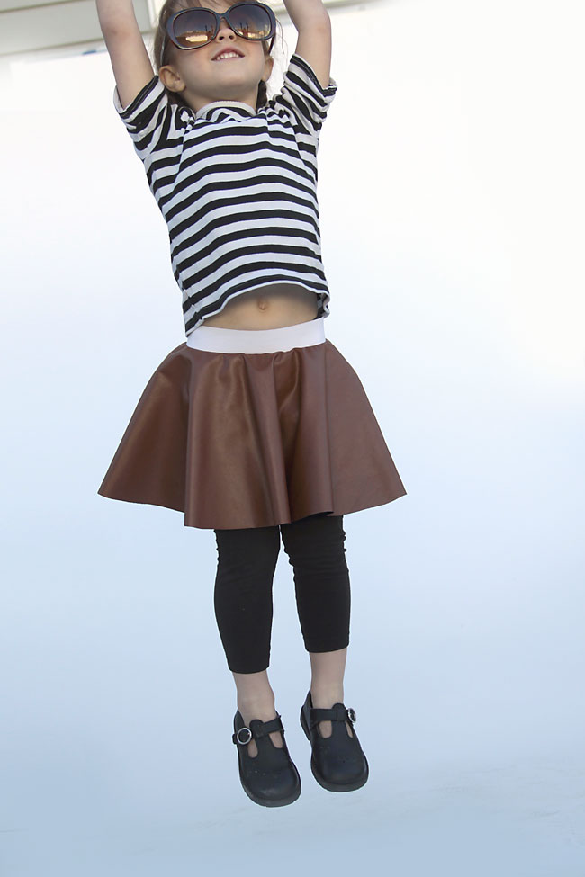 A girl jumping in a faux leather circle skirt