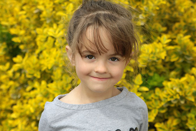 A little girl in front of yellow flowers