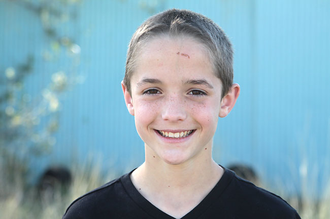 A boy standing further in front of the wall so the wall is blurred in the background