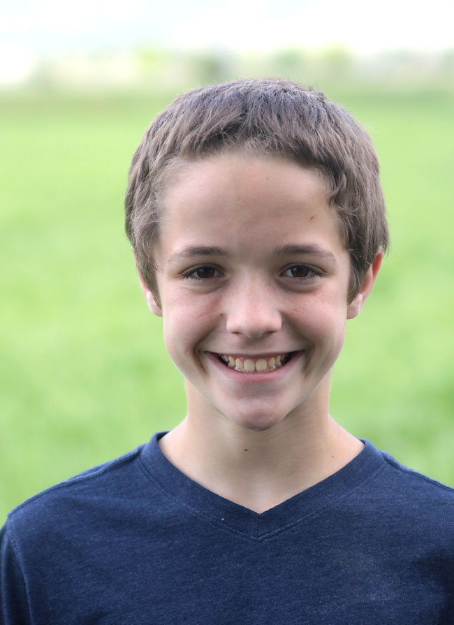 A boy standing outside with most of face in shadow