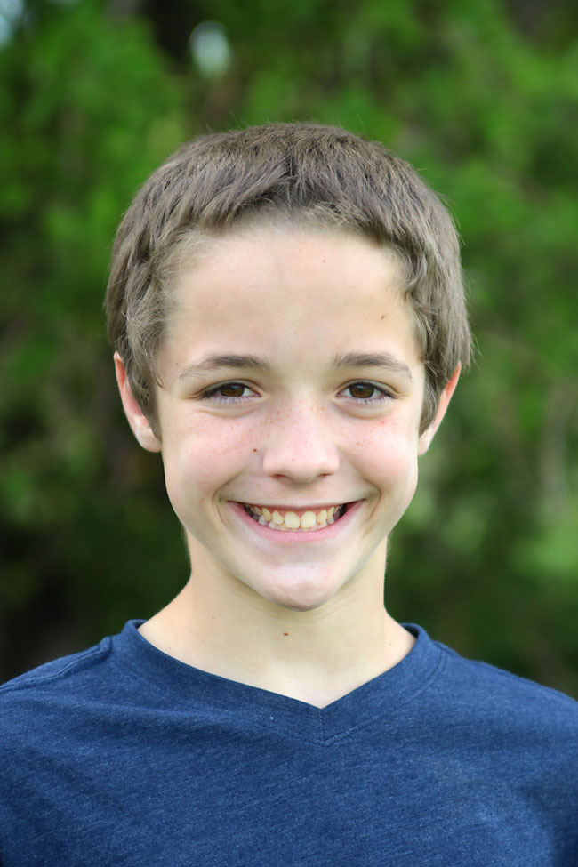 A young boy standing outside with his face evenly lit