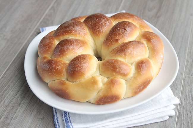 A golden brown loaf of braided enriched bread on a plate