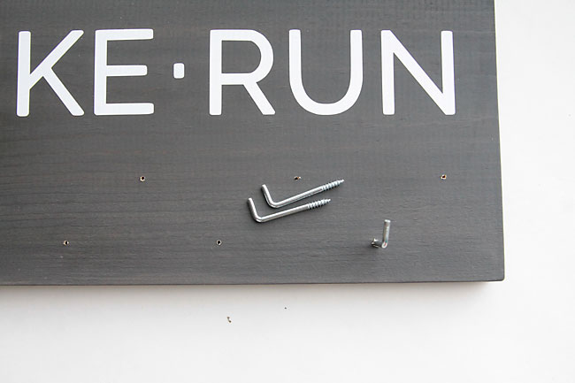 screwing hooks into holes drilled in sign