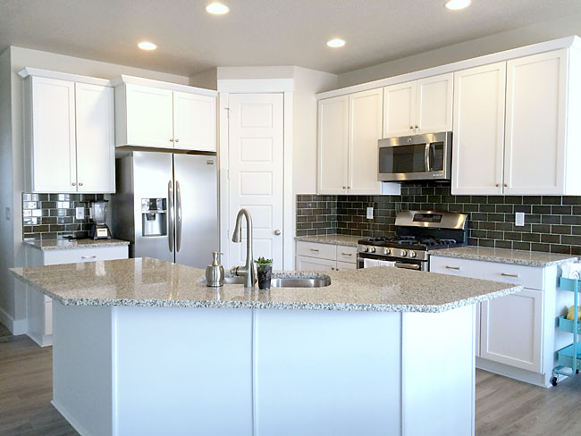 A large white kitchen with stainless steel appliances