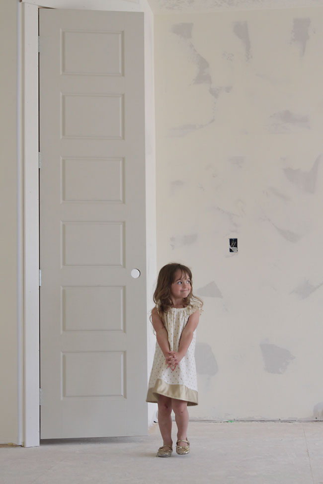 A girl in front of a door in an unfinished house