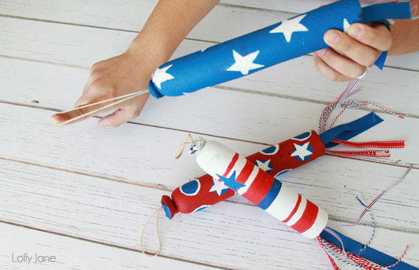 Hands holding foam slingshot that\'s been painted blue with white stars for 4th of July craft