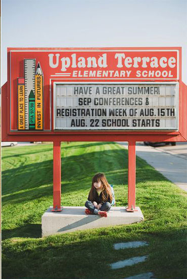 Girl sitting under an elementary school sign
