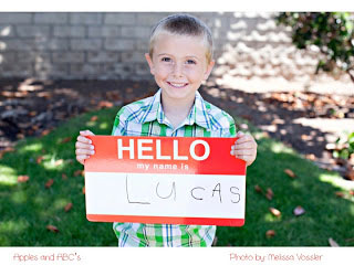 A little boy holding a sign that says hello my name is lucas