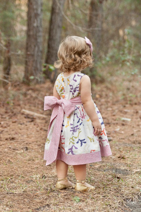 A little girl that is standing in the grass wearing cute dress made from a free sewing pattern
