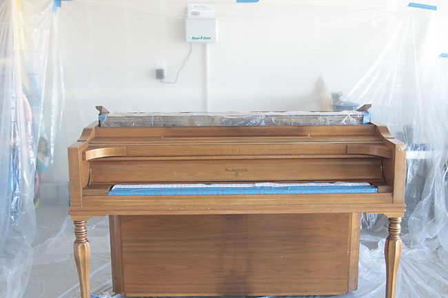 wood piano taped and prepped to be painted