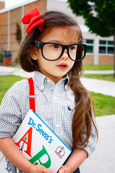 A girl wearing glasses holding a Dr Suess book