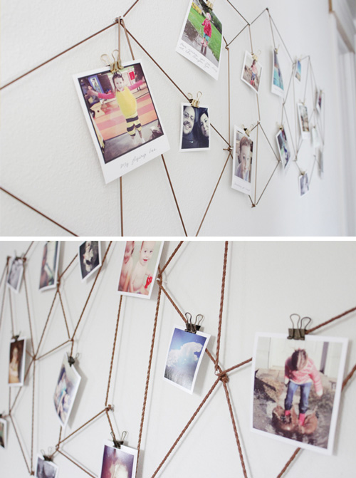 Photos hanging from string that\'s making geometric shapes on a wall