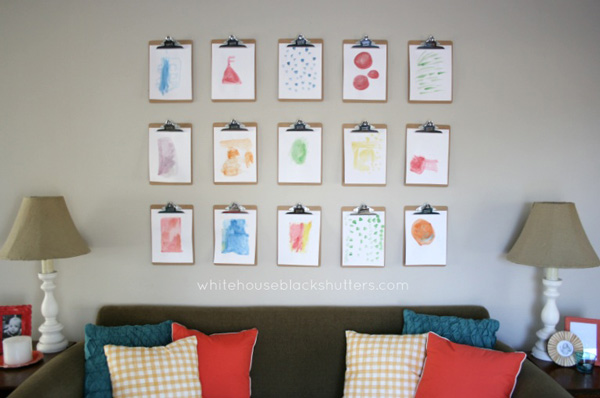Wood clipboards holding art prints hanging on a wall above a sofa