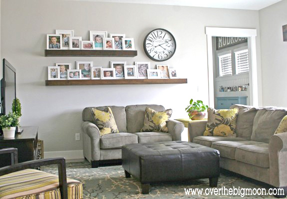 A living room filled with furniture and two long shelves on the wall filled with framed photos