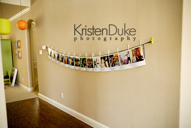 String hanging across a long wall with photos hanging from it