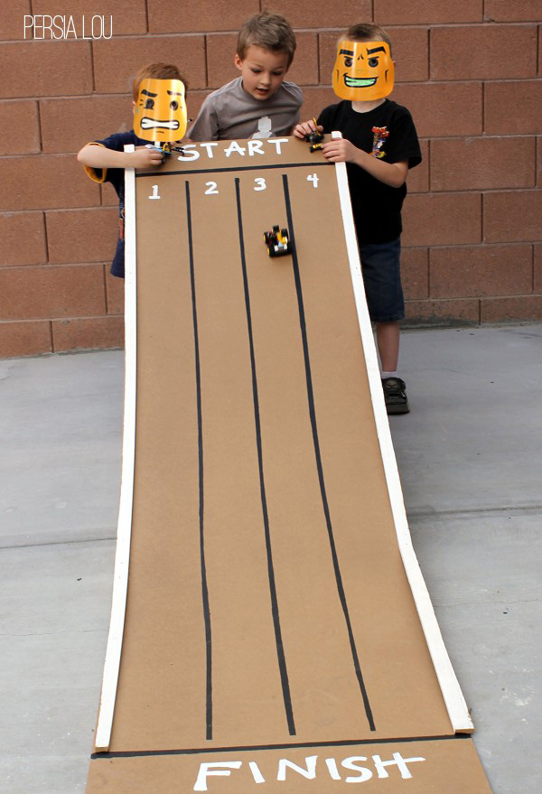Boys holding a long cardboard track for toy cars