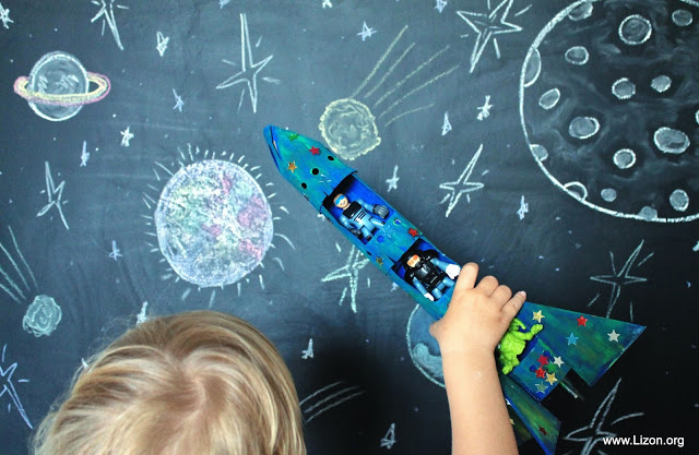 Kid playing with a rocket made from cardboard