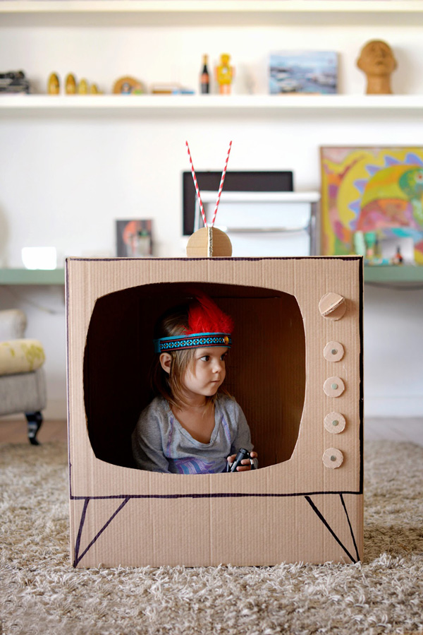 Little girl sitting inside a box made to look like a TV