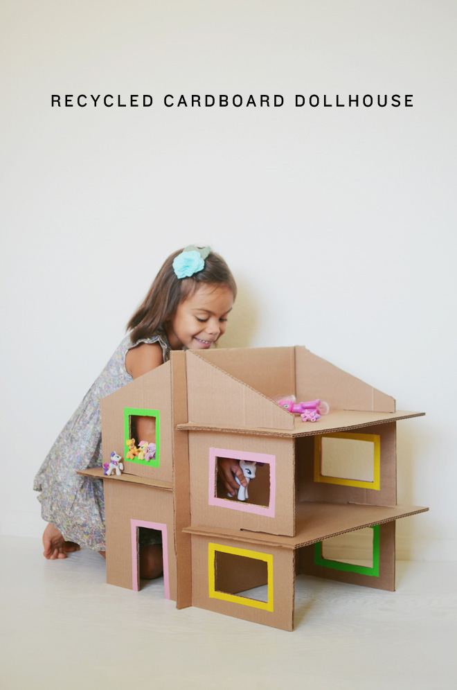 Girl playing with doll house made from cardboard