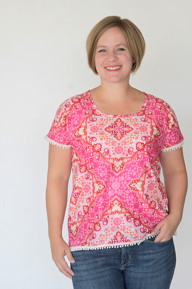 Woman smiling with a pink blouse with pom pom trim