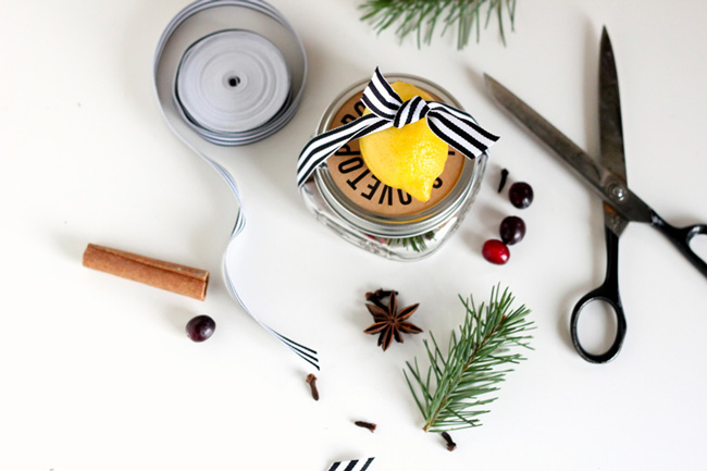 A jar of stovetop potpourri along with ribbon and potpourri ingredients on a table