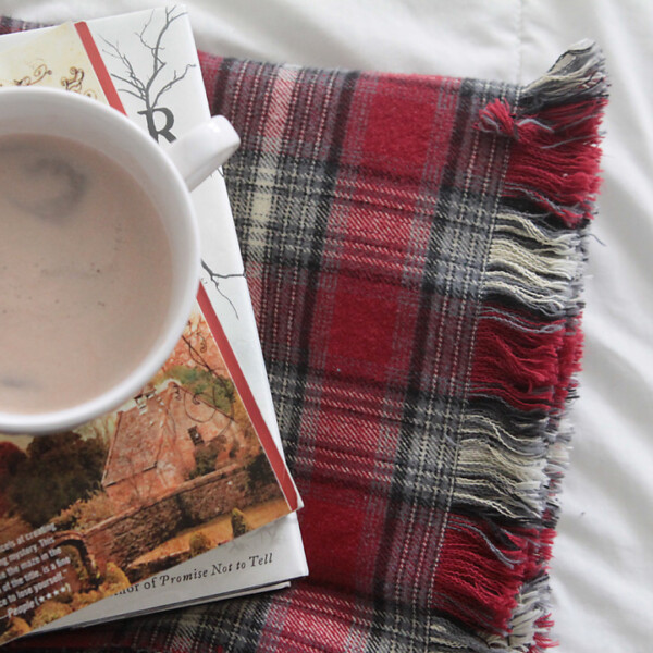 DIY Fringed flannel throw blanket on a bed with books and cocoa