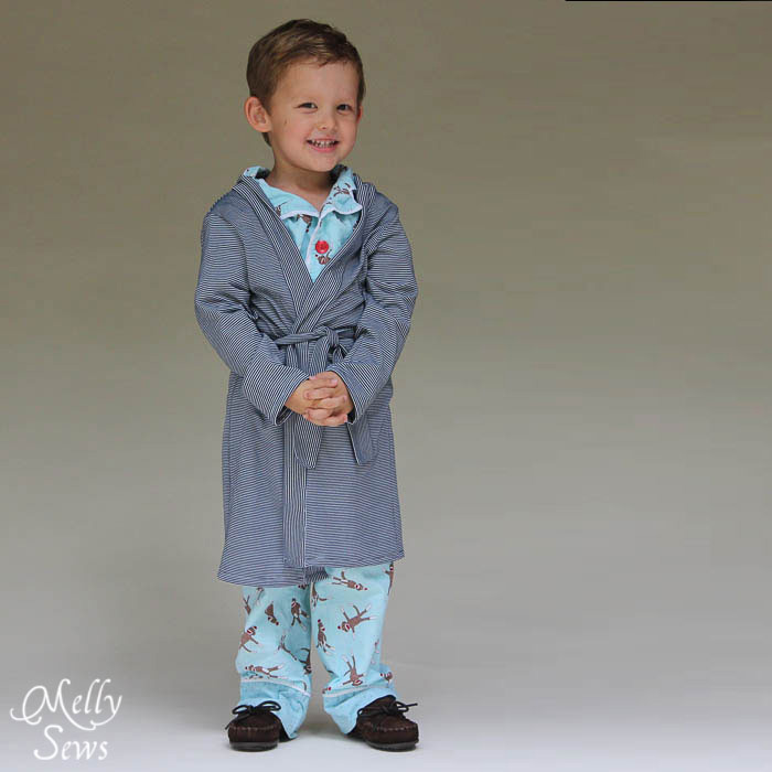 A little boy wearing blue pajamas and a robe