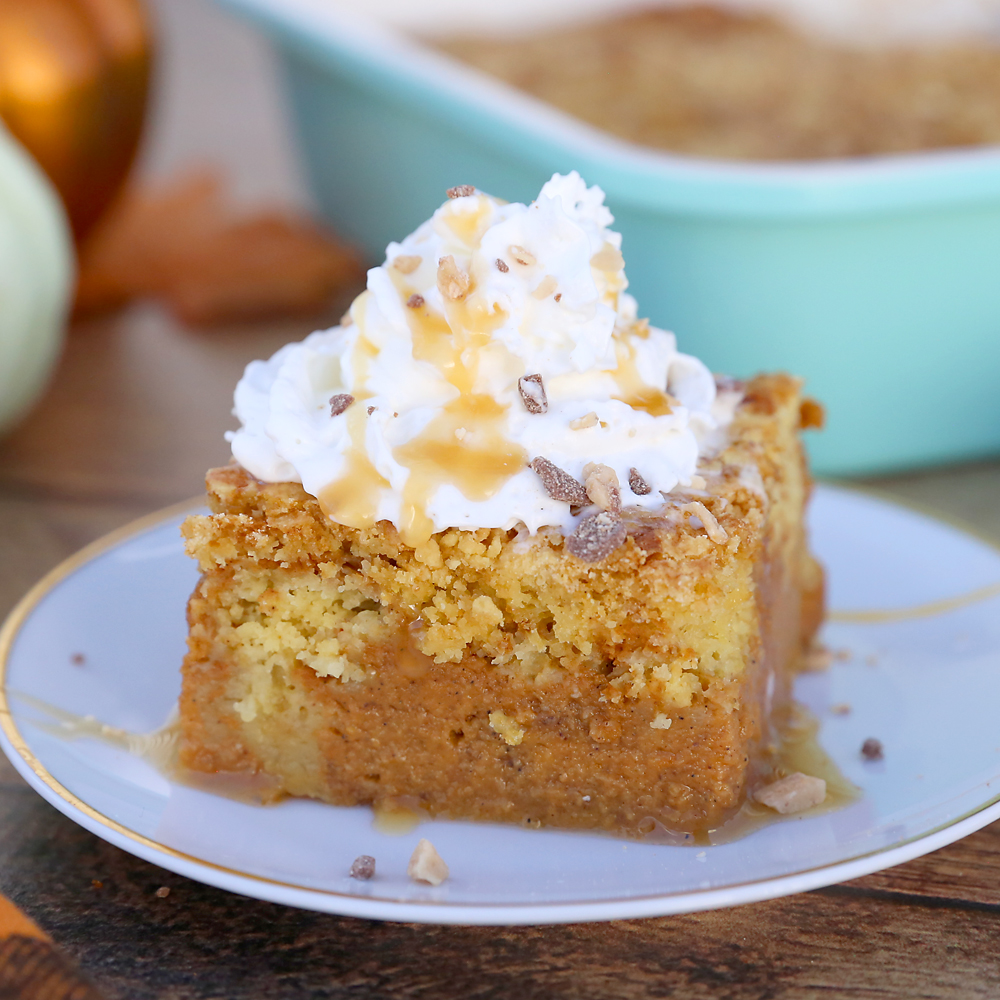 A piece of pumpkin pie cake on a plate, topped with whipped cream and toffee bits