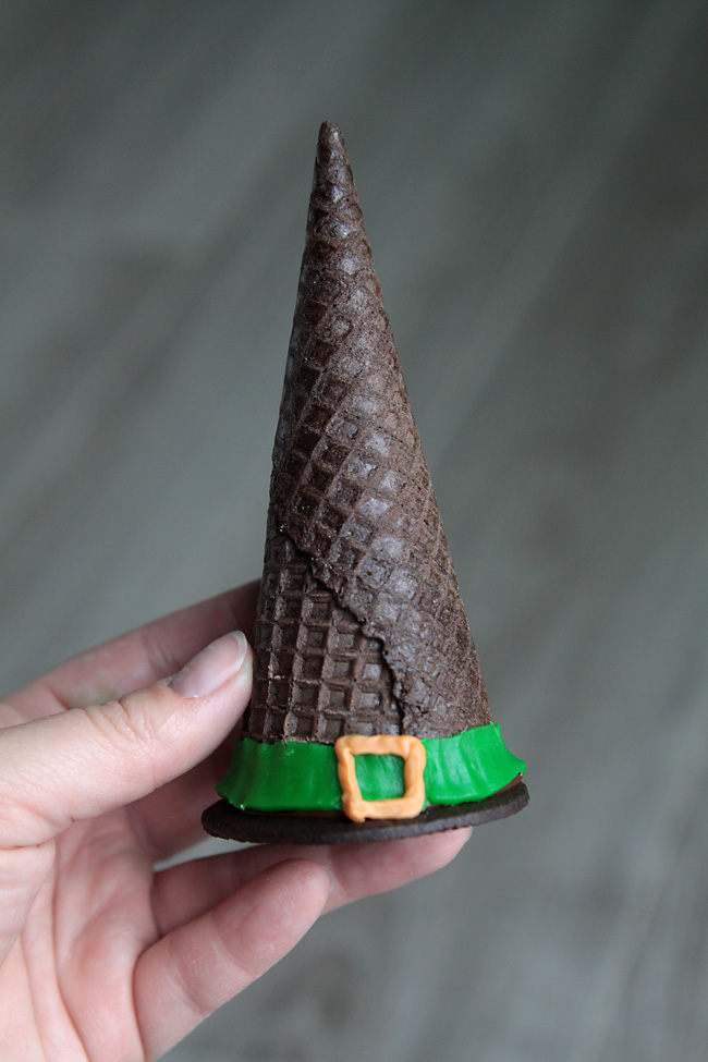 Hand holding a cookie made with an upside down ice cream cone decorated to look like a witch hat