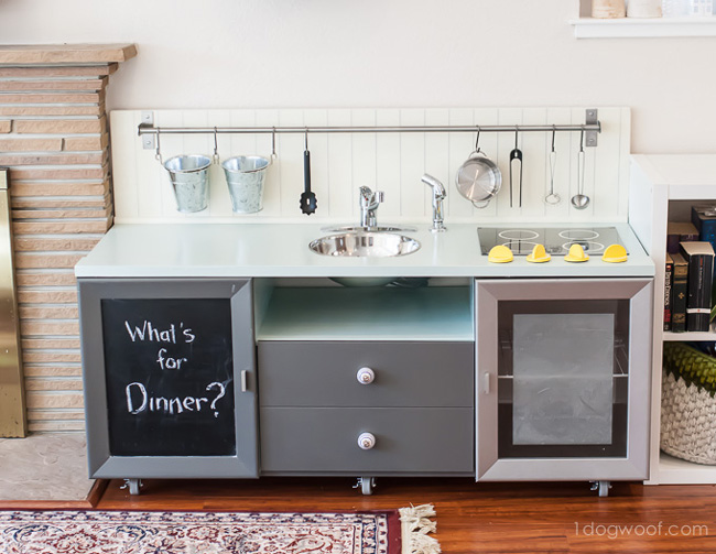 Play Kitchen made from a TV stand with bar on the wall for utensils to hand from